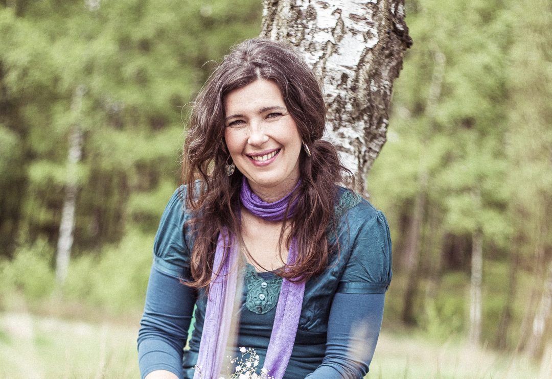 Ebrina Haga buiten tegen een berkenstam