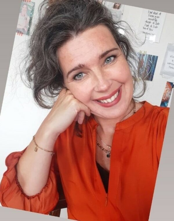Ebrina in een oranje blouse in haar studio