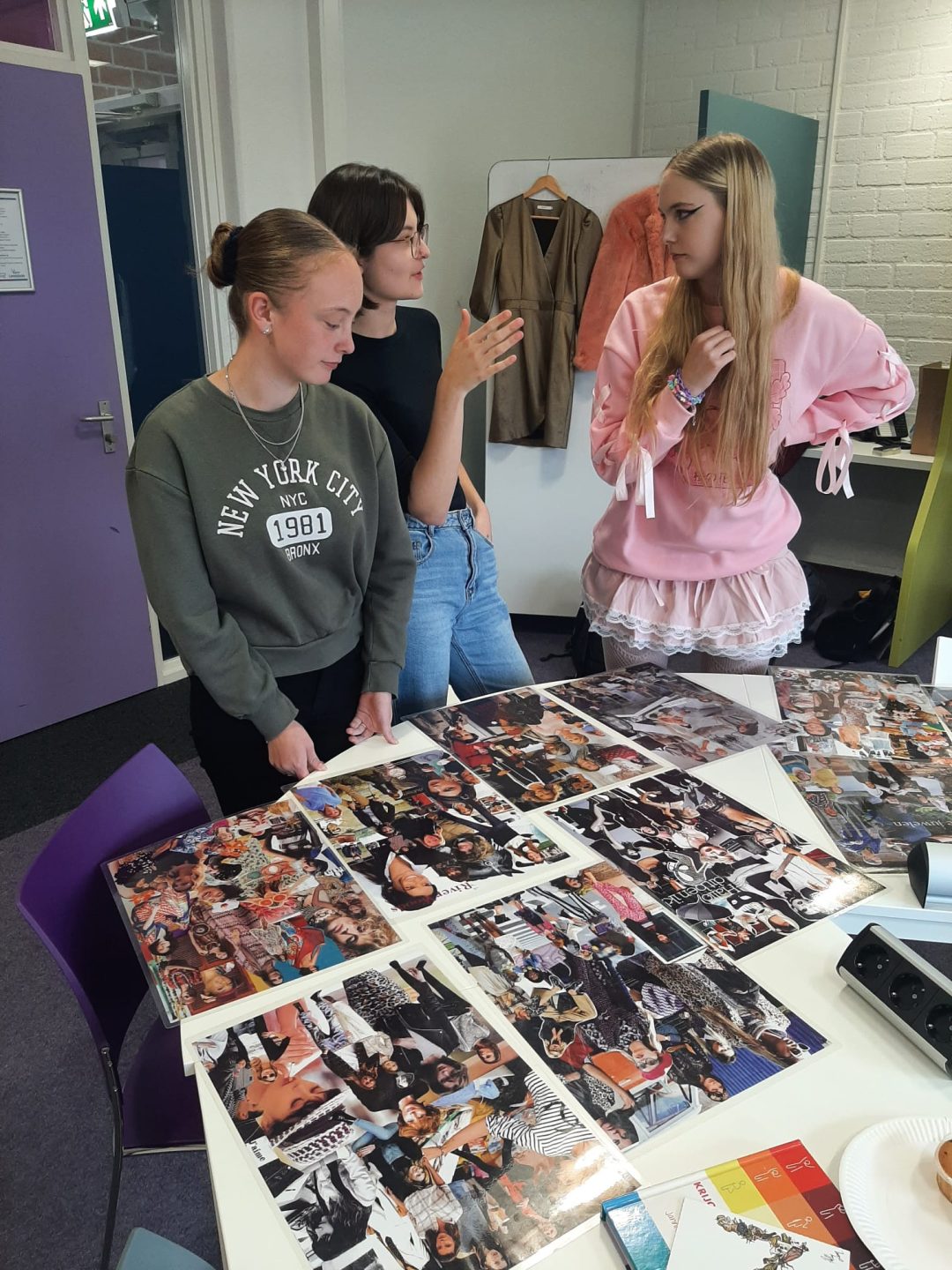 Drie deelnemers aan een workshop bij een tafel met kleurenfoto's