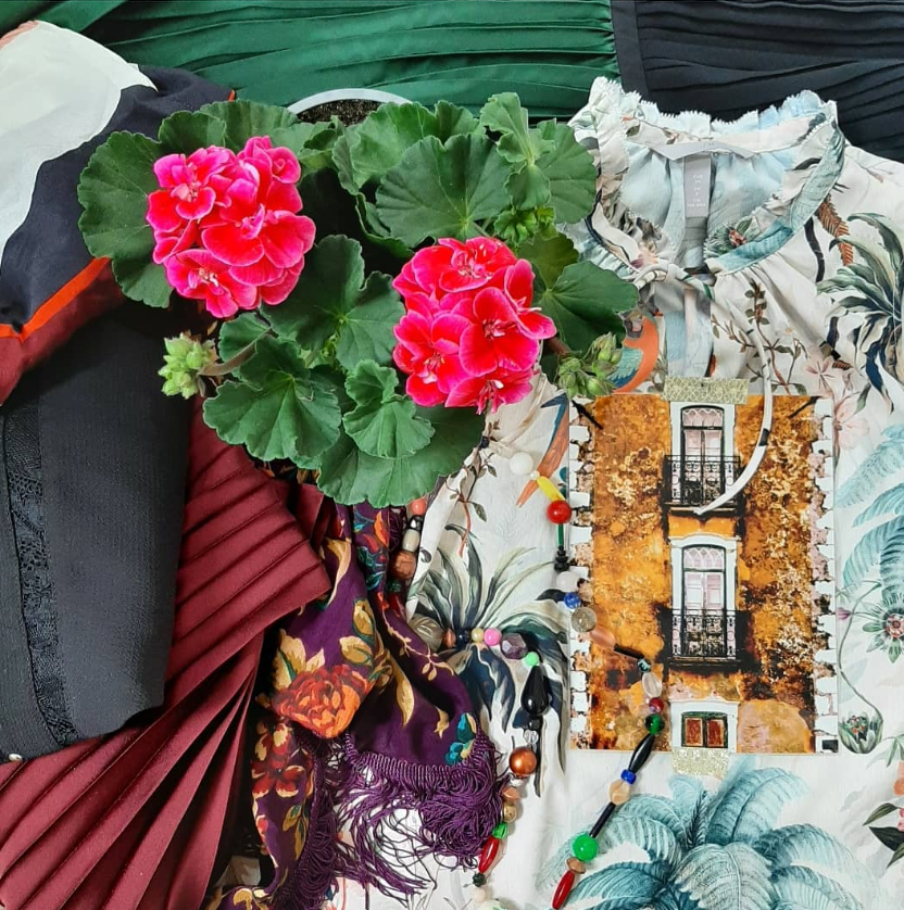 Kleding met dessins, roze geraniums en een foto van een gevel